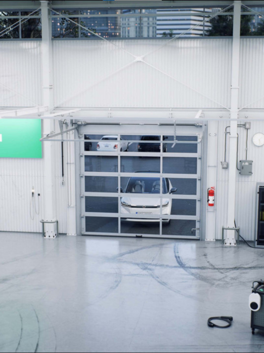 Fotorealistische 3D-Visualisierung einer modernen Werkstatt mit weißem Auto im Rolltorbereich, Reifenstapeln und Werkstattequipment – professionelles 3D-Design für realitätsnahe Szenen